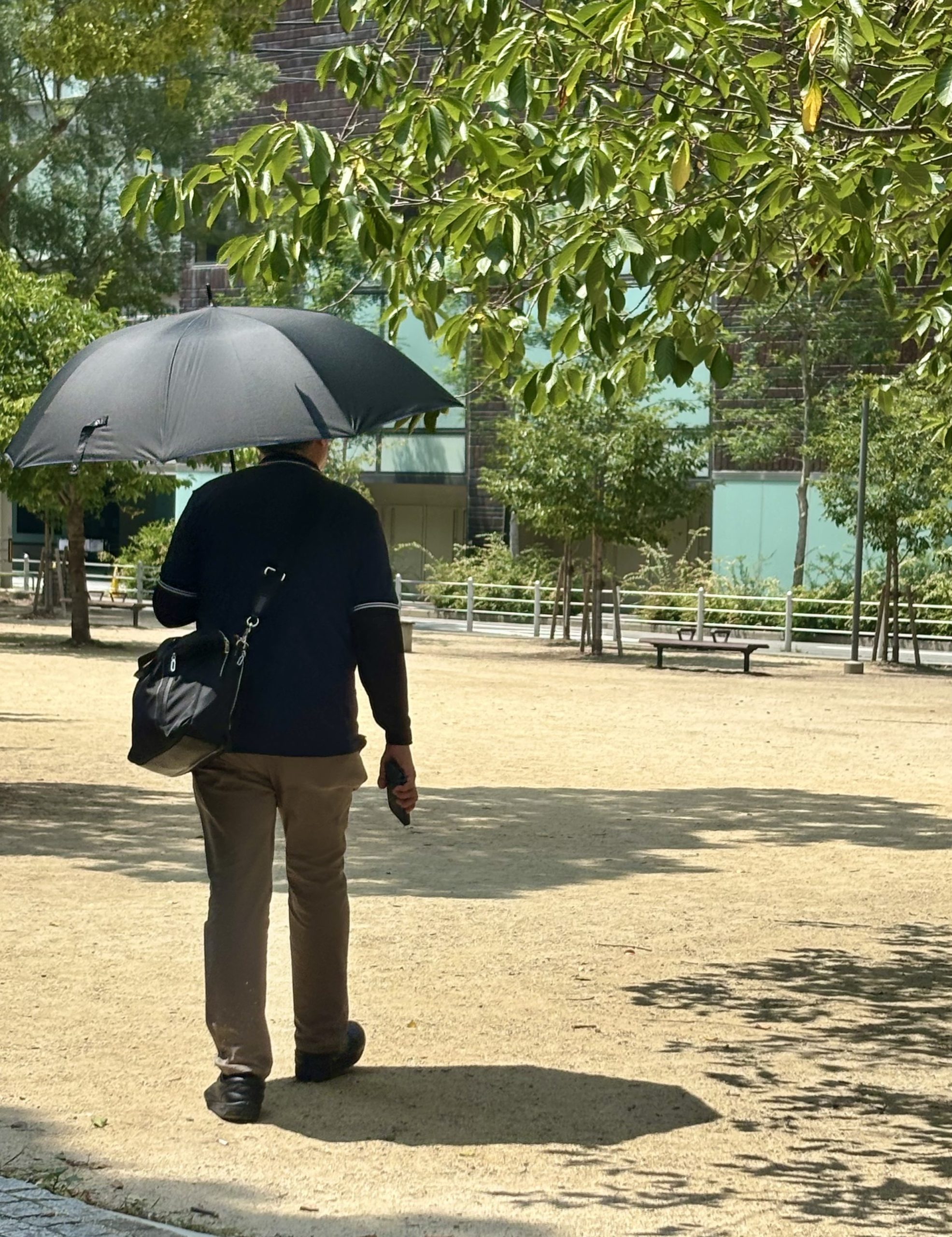 長傘タイプの日傘をさして歩く男性